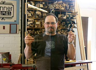 Travis Tanner of Tanner Frames demonstrates the difference between regular glass and museum quality glass